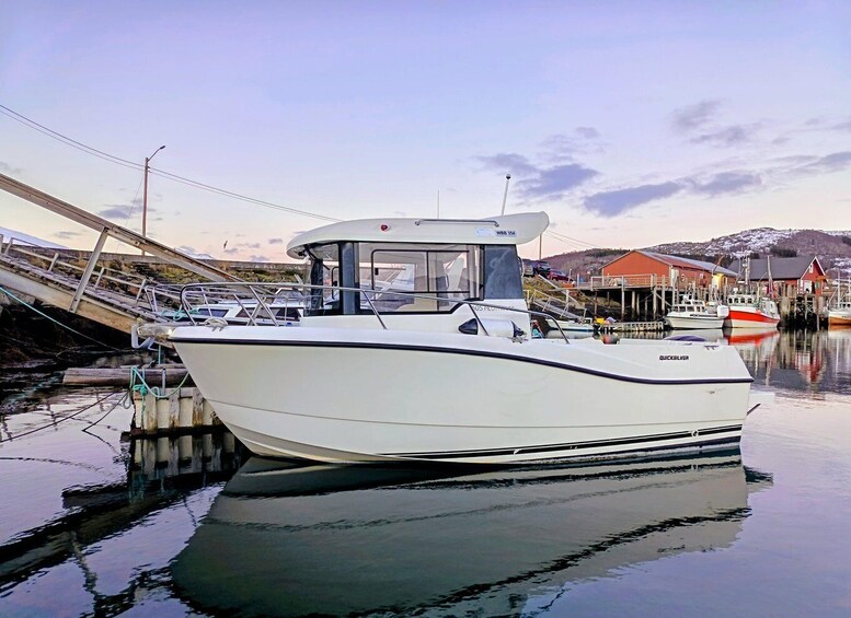 A white boat docked at a marina with a bridge in the background and a building with a red roof. 5