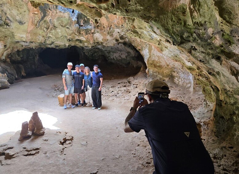 A group of people inside a cave with rocky walls and a dirt floor. 3