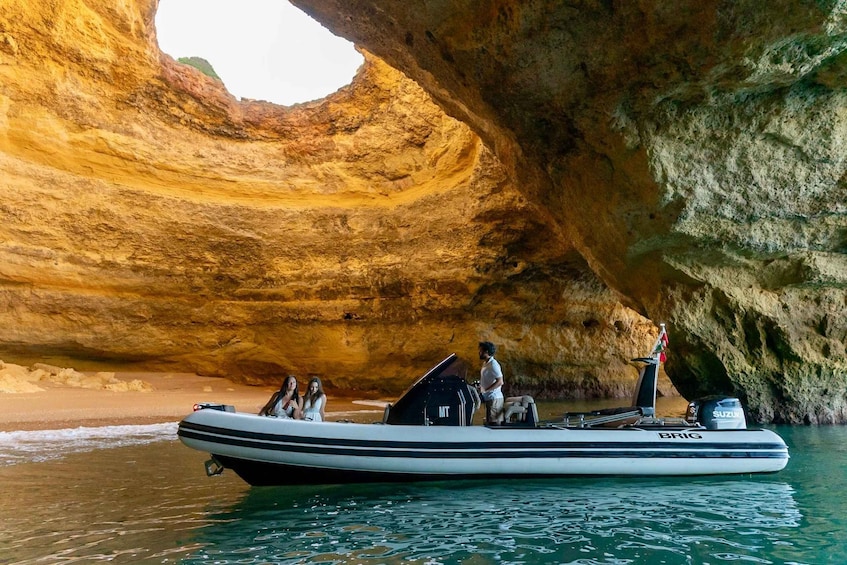 A boat with people on a rocky coastline with a cave-like formation. 1