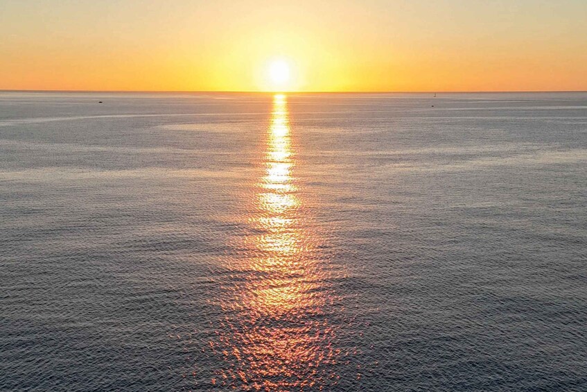 A calm sea at sunset with a visible sun reflection on the water's surface. 5