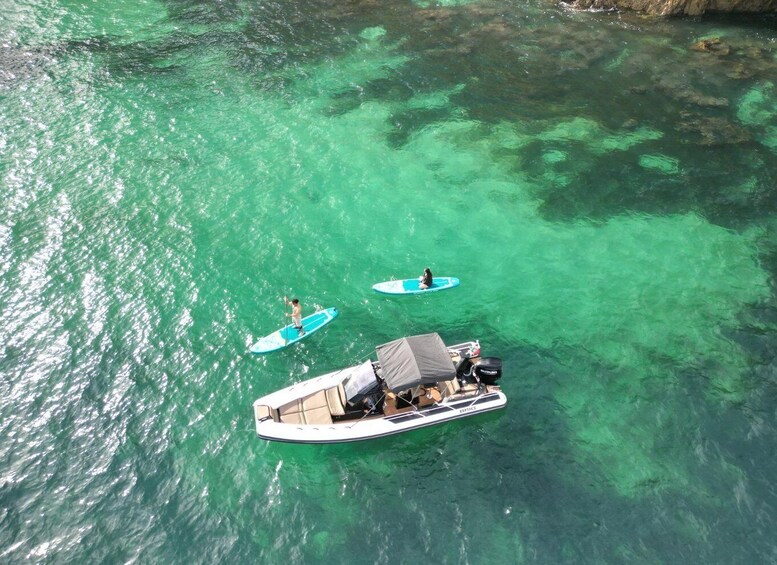A boat with two people paddleboarding in clear turquoise water. 2