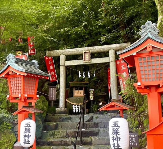 A traditional Japanese shrine with red torii gates, stone steps, and hanging decorations. 2