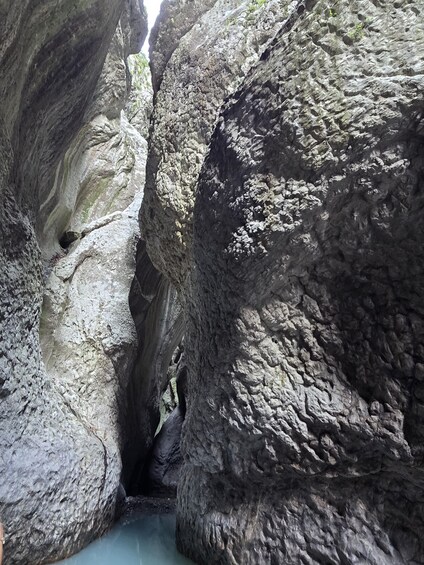 A narrow canyon with rugged rock formations and a visible water stream. 4