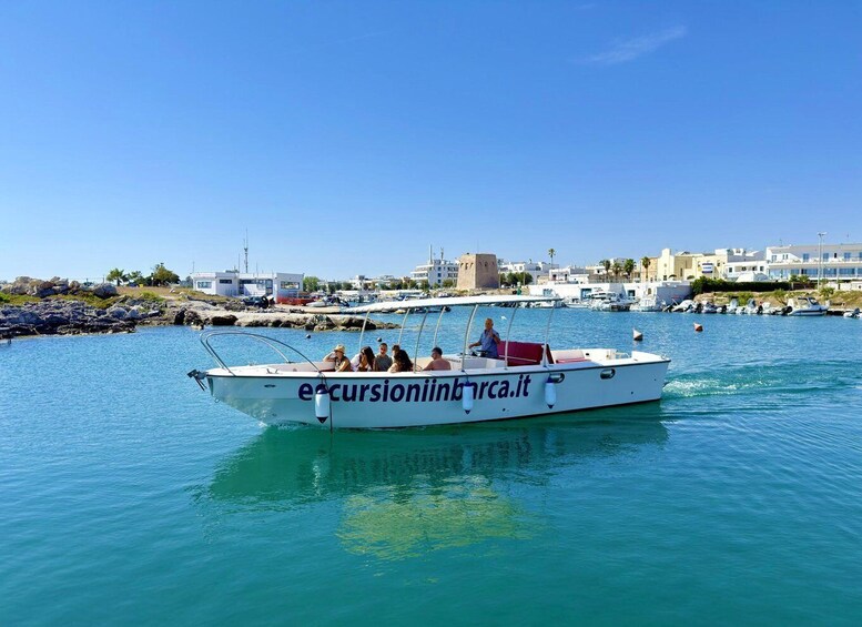 A boat with people on it, docked at a marina with buildings in the background. 3
