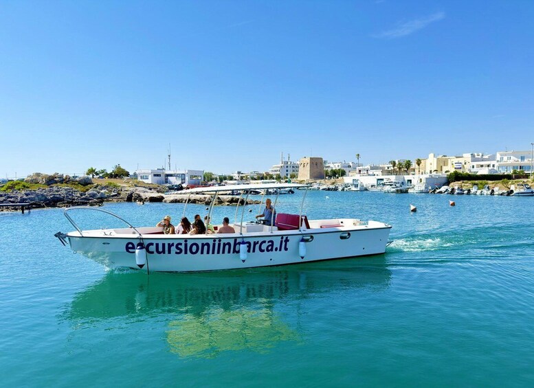 A boat named 'ecursioniniinbarca.it' on calm waters with a marina and buildings in the background. 2