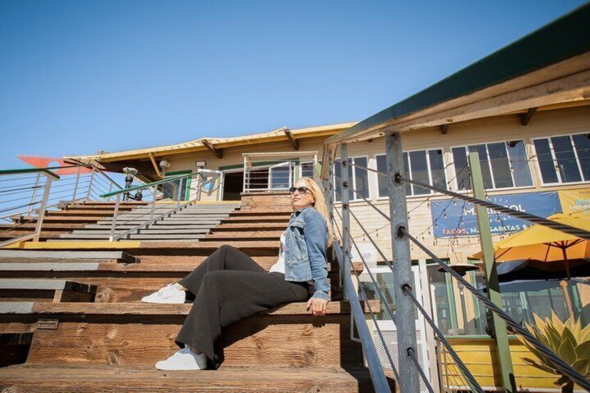 A person sitting on bleachers with a building and a sign in the background. 4