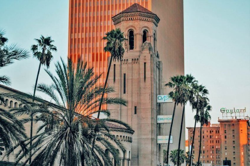 A tall building with a clock tower, palm trees, and signs for 'Church' and 'Gayland.' 1