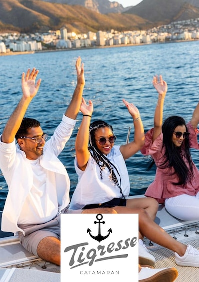 Three people on a boat with their hands raised, a cityscape in the background, and the logo 'Tigresse CATAMARAN' at the bottom. 1