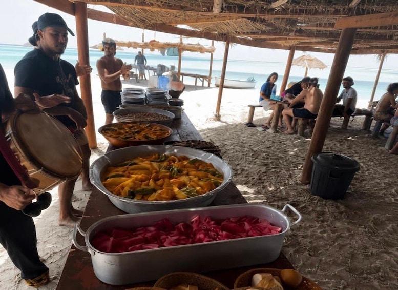 A beachside food stall with various dishes and a drum. 5