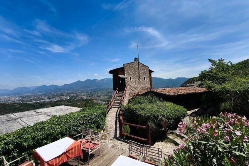 A stone tower with a staircase leading up to it, surrounded by greenery and overlooking a valley. 1