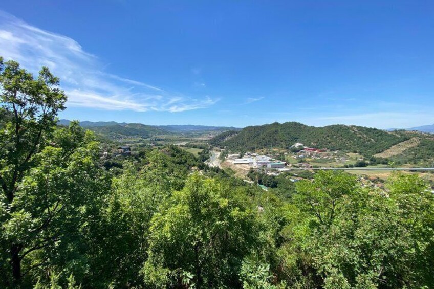 A valley with dense green trees, rolling hills, and a clear blue sky. 2