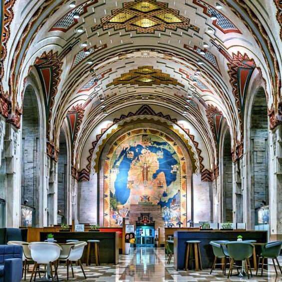 An interior with a detailed mural, arched ceilings, and modern seating. 3