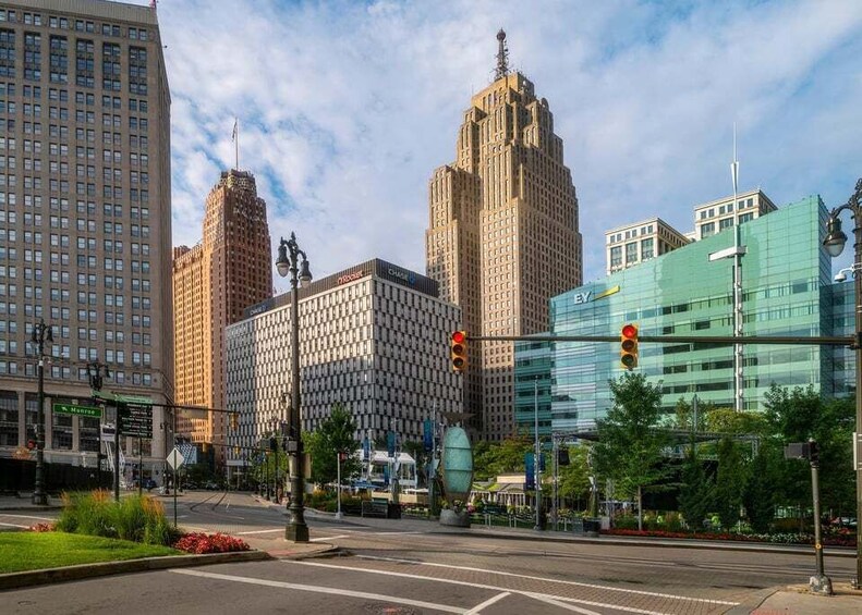 A cityscape with tall buildings, a traffic light, and a green traffic island. 2