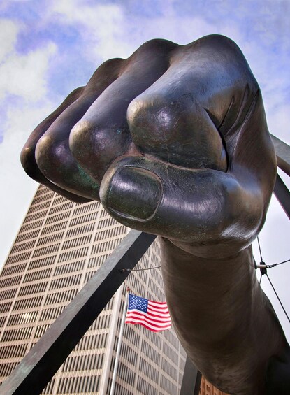 A large metallic fist sculpture with an American flag in the background. 5