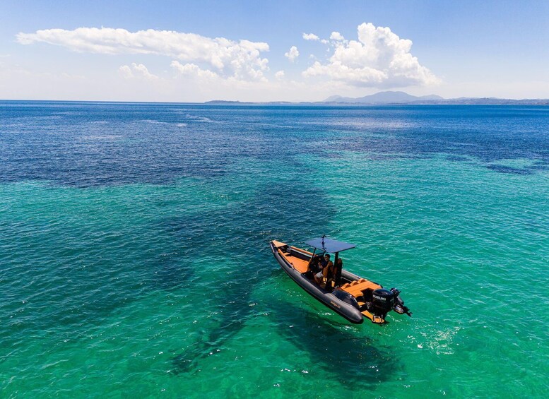 A boat on clear turquoise water with a mountainous horizon. 2