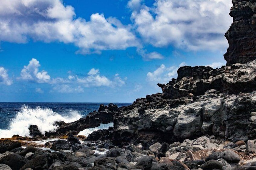 A rocky coastline with waves crashing against the rocks under a partly cloudy sky. 2