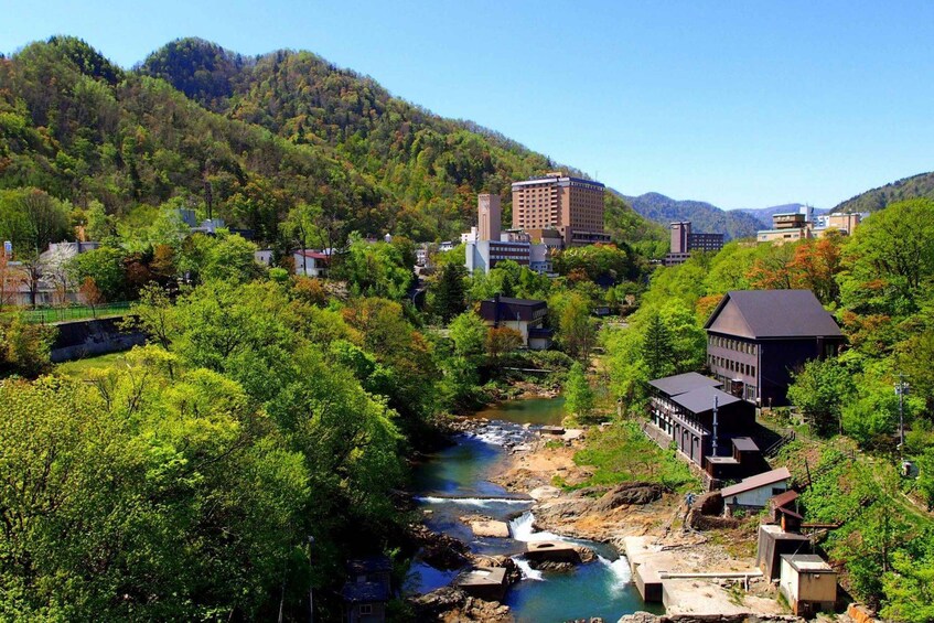 A river flowing through a valley with buildings and a mountain in the background. 5