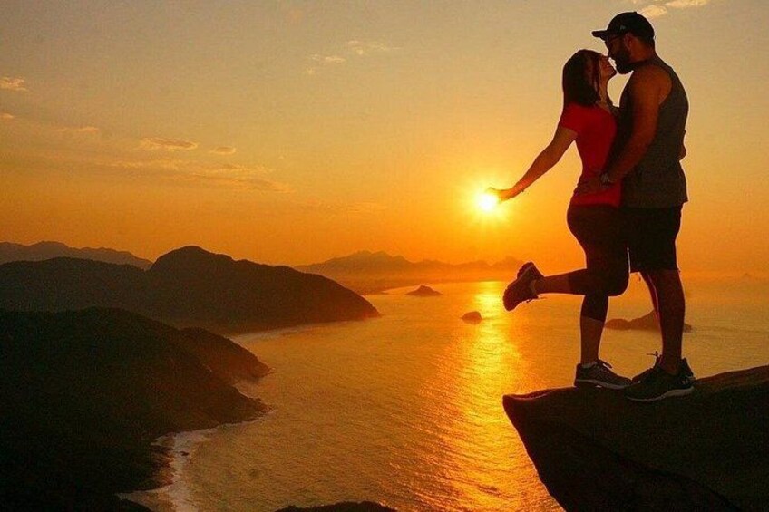 A couple embracing at sunset with a coastal landscape in the background. 3