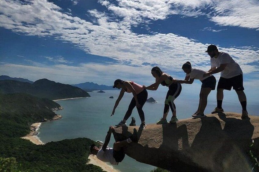 A group of people on a cliff overlooking a coastal landscape with mountains in the background. 2