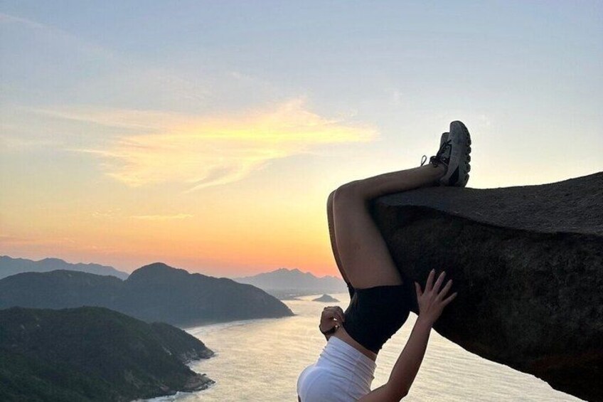 A person climbing a rock with a sunset in the background. 3