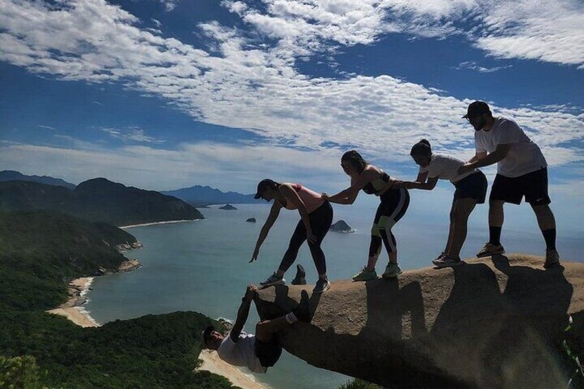 A group of people on a cliff overlooking a coastal landscape. 1