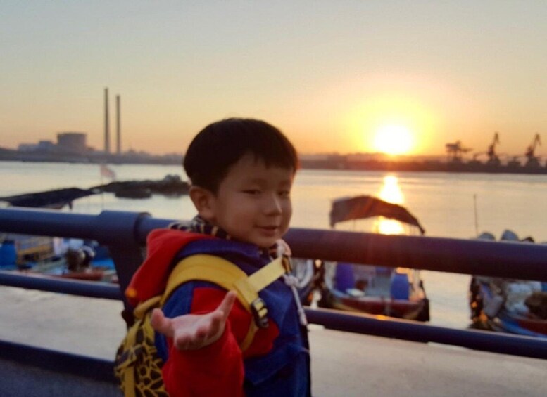 A child with a backpack by a waterfront at sunset. 4