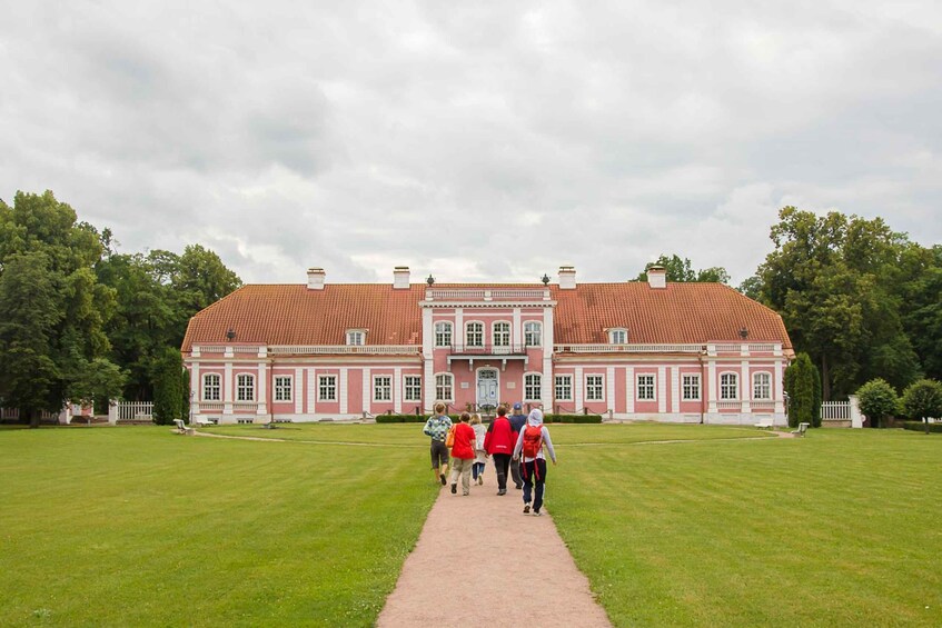 A large, red-tiled building with a central entrance, surrounded by a well-maintained lawn and trees. 4