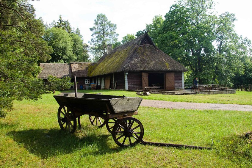 A thatched-roof building with a wooden wheelbarrow in front. 3