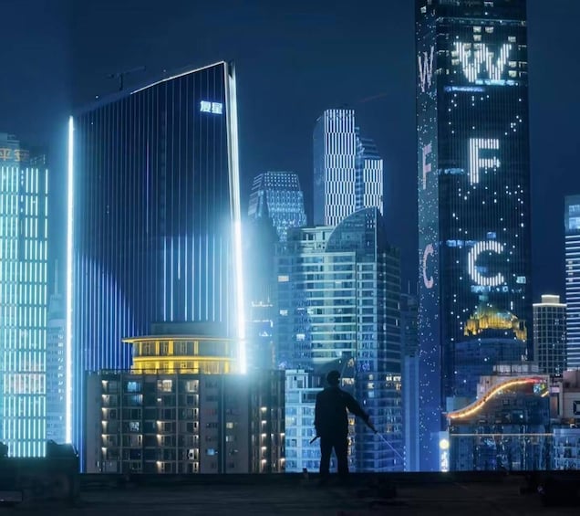 A nighttime cityscape with illuminated skyscrapers and a person standing on a rooftop. 1