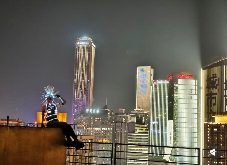 A cityscape at night with illuminated skyscrapers and a person sitting on a ledge. 3