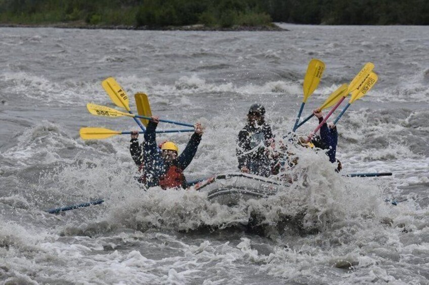 Two people in a kayak navigating rough waters with paddles. 5