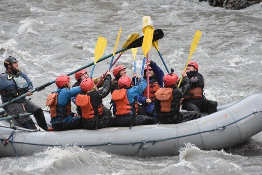 A group of people in a raft navigating rough waters. 3
