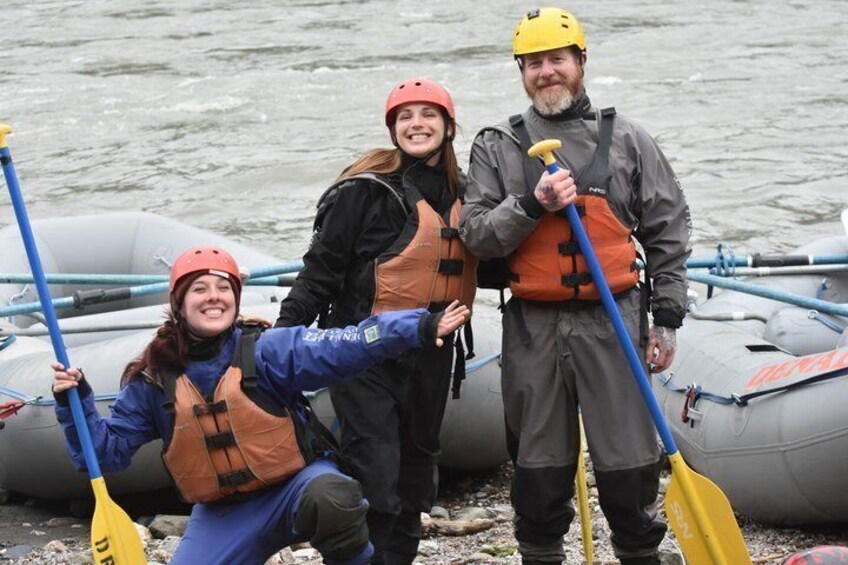 People in life jackets and helmets near inflatable boats on a body of water. 2
