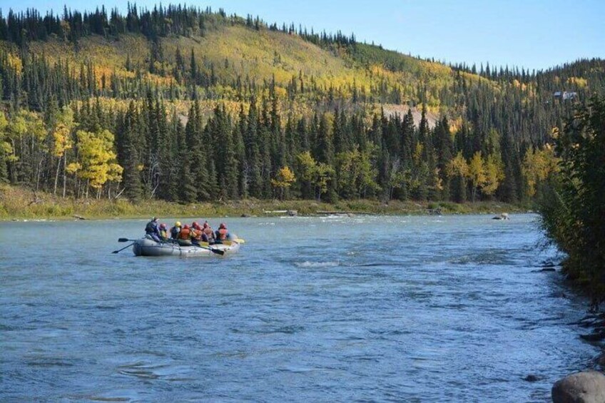 A group of people in a raft on a river surrounded by forested hills. 5
