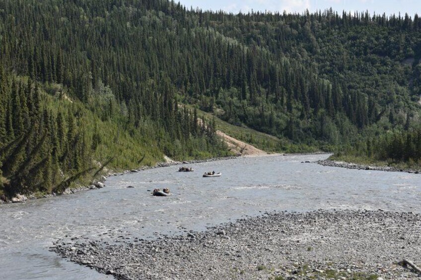 A river with boats, surrounded by dense forest and a mountain in the background. 5
