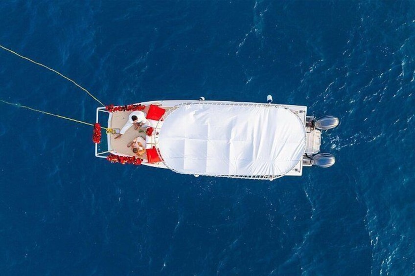 A boat with a white cover, red cushions, and a person standing at the bow. 2