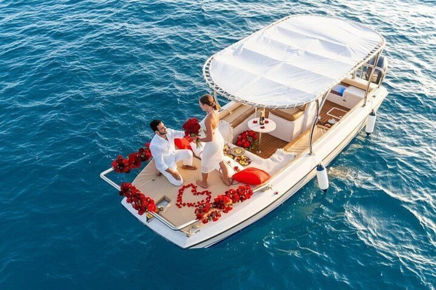 A boat with a white canopy, red flowers, and a couple sitting on the deck. 1
