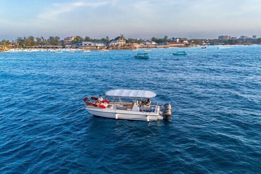 A boat with passengers on a calm sea, with other boats and a distant shoreline in the background. 3