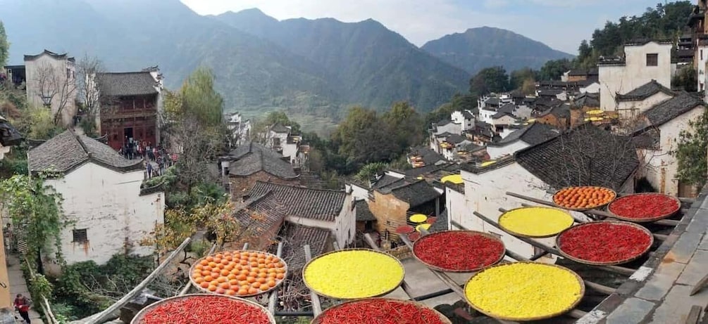 A traditional village with terraced houses and large bowls of red and yellow peppers. 1