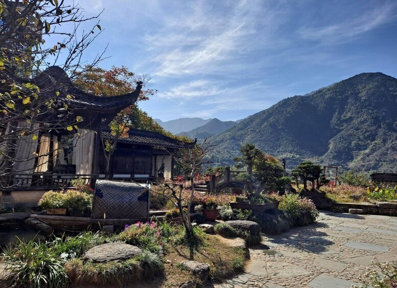 A traditional Japanese building with a tiled roof, surrounded by a garden with rocks, plants, and a stone pathway. 4