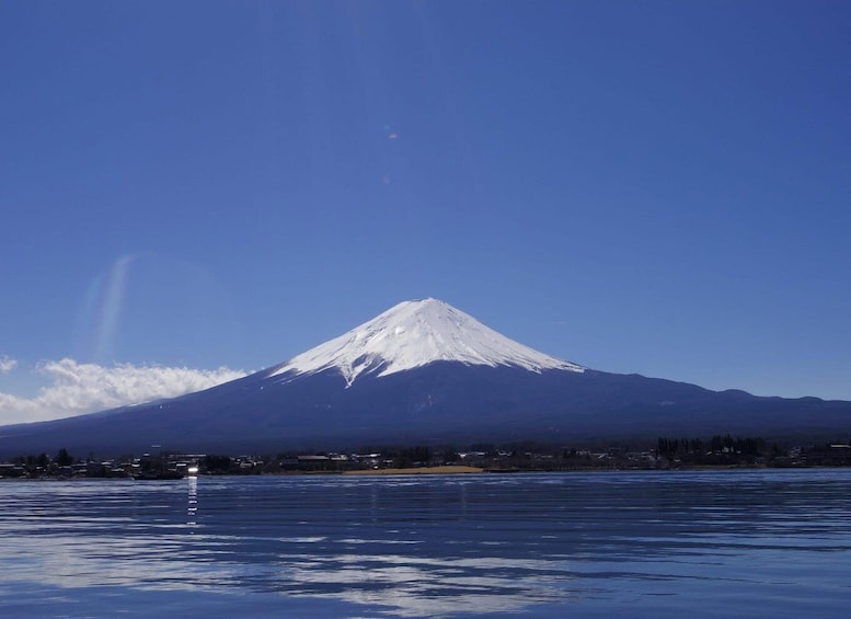 A snow-capped mountain, a clear sky, and a calm body of water reflecting the mountain. 4