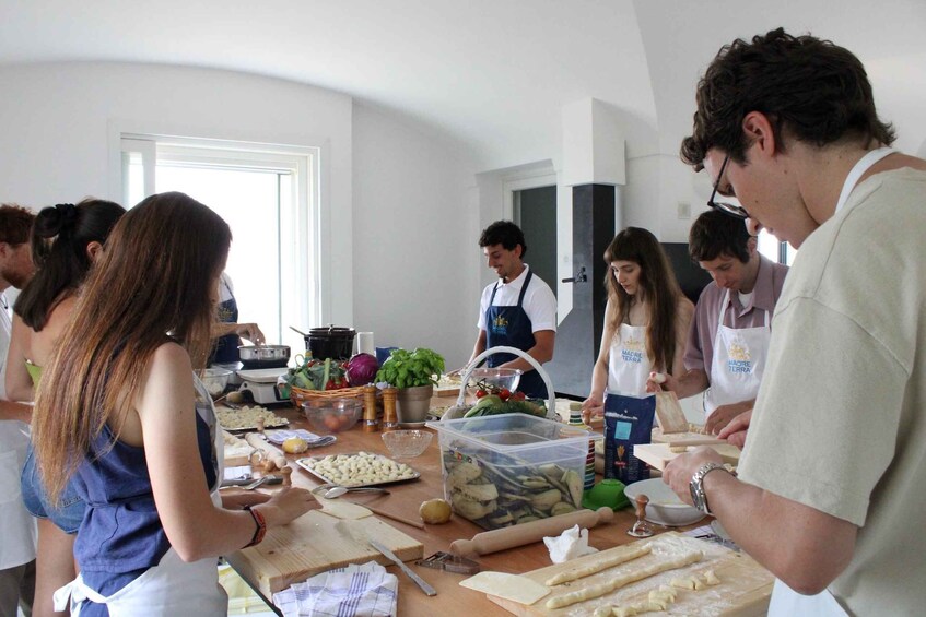 A group of people engaged in a cooking activity with various ingredients and kitchen tools on a table. 4