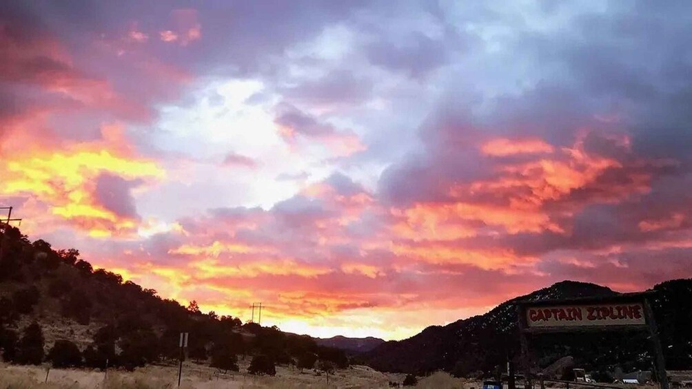 A sunset with a vibrant sky, a mountain range, and a sign for 'CAPTAIN ZIPLINE.' 1