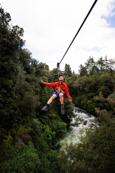 A person zip-lining through a forested area with a river below. 4