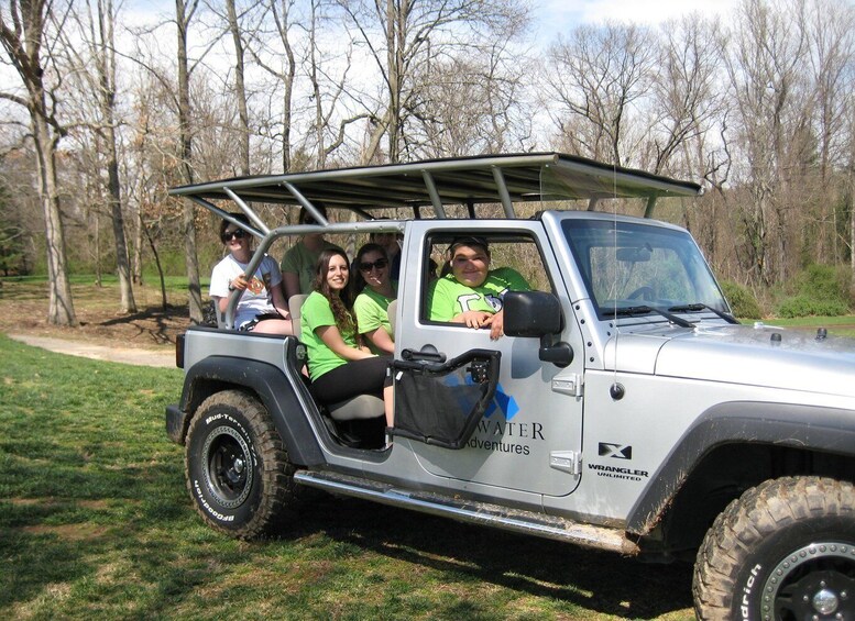 A silver off-road vehicle with 'WATER adventures' and 'WRANGLER UNLIMITED' branding parked in a grassy area with trees in the background. 3