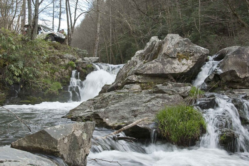A waterfall cascading over rocks in a forested area. 1