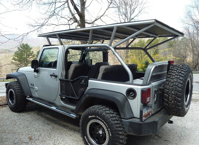 A rugged off-road vehicle with a roof rack, large tires, and a spare tire mounted on the back. 2