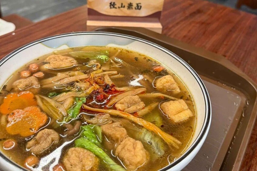A bowl of soup with meatballs, vegetables, and a clear broth. 4