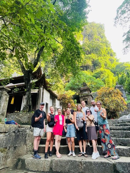 A group of people standing on stone steps in a lush, green area with ancient stone structures in the background. 2