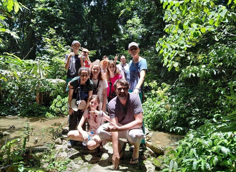 A group of people posing in a lush, green forested area with a stream. 5